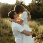 Пара обнимается на закате в поле