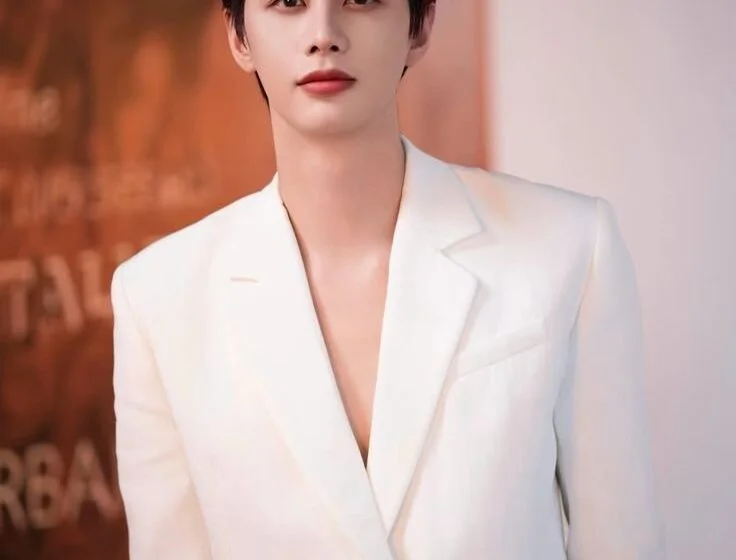 Молодой человек в белом костюме на фоне абстрактного искусства.