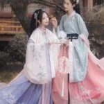 ЧУ ЧЖАО – ТОМ 1: Путь сквозь пустоши; Глава 22.1 – Семья Две женщины в традиционных азиатских нарядах в саду