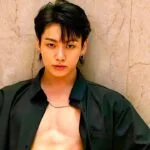 Молодой человек в черной рубашке на фоне мраморной стены