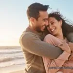 Пара обнимается на пляже на закате, романтический момент