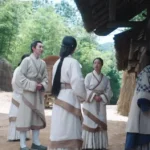 Глава 5. Одурманивающий аромат женщины Группа людей в традиционной одежде возле деревенского дома