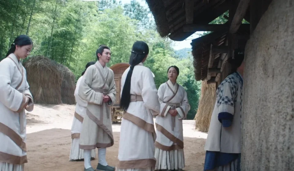 Группа людей в традиционной одежде возле деревенского дома