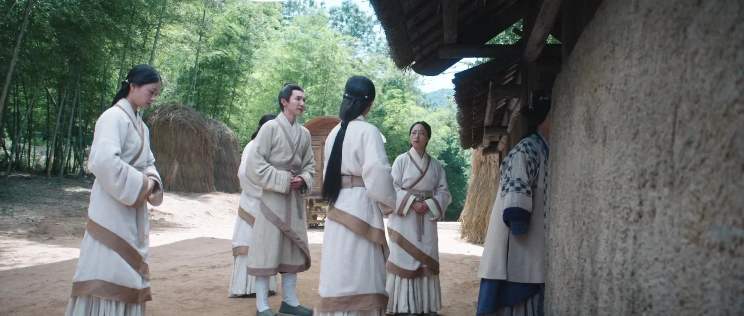 Группа людей в традиционной одежде возле деревенского дома