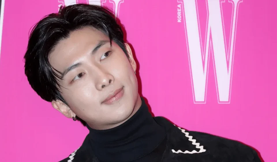 Человек на розовом фоне, стильная прическа и черная одежда