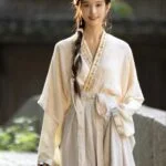 Женщина в традиционной одежде с длинной косой, стоящая на улице.