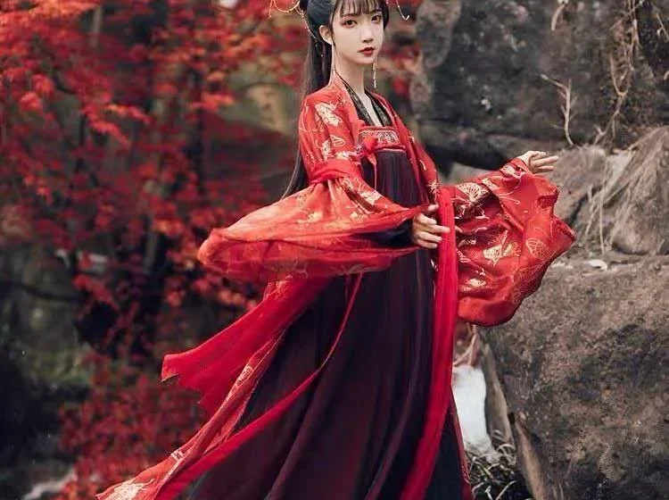 Женщина в красном традиционном платье на фоне осенних деревьев