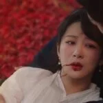 Глава 38: Оружие готово к бою, надежды не видно Сцена из драматического фильма с женщиной и мужчиной на фоне красных лепестков.