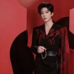 Молодой человек в стильном черном костюме на красном фоне