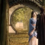 Двое в традиционной одежде в саду с арками