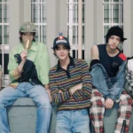 Группа молодых людей в модной одежде на фоне здания