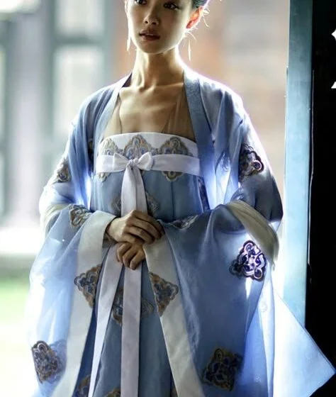 Женщина в традиционном азиатском платье стоит у окна