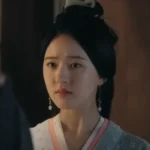 Женщина в традиционной одежде смотрит с серьёзным выражением