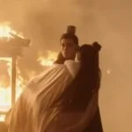 Сцена из исторической драмы с горящим зданием на фоне.