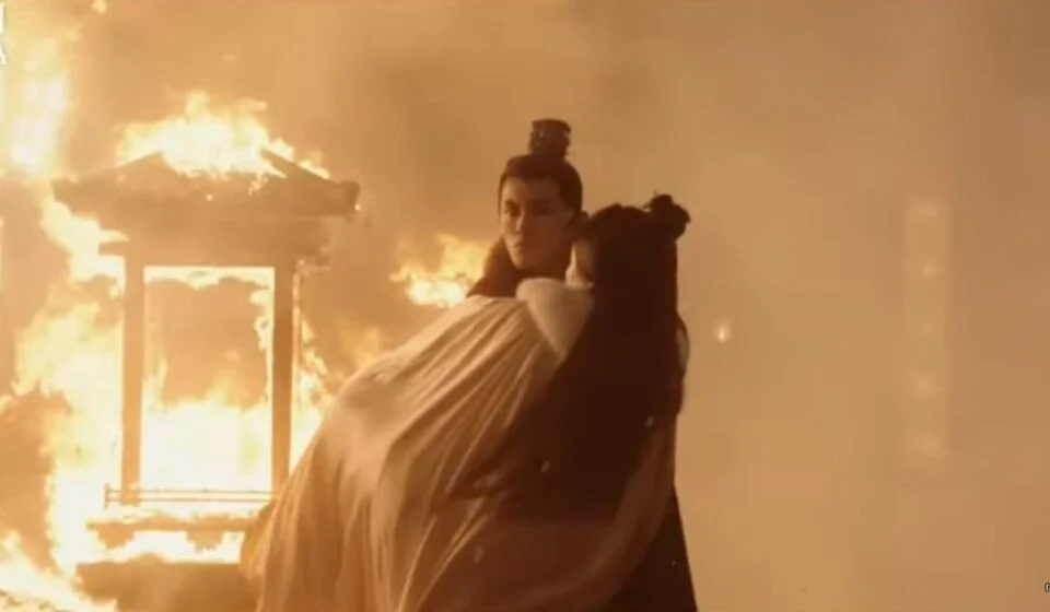 Сцена из исторической драмы с горящим зданием на фоне.