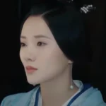 Женщина в традиционной одежде с серьгой, смотрит в сторону.