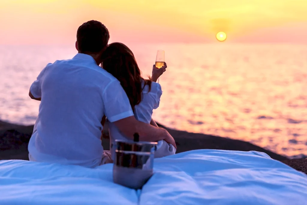 Пара наслаждается закатом у моря с бокалом вина