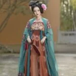 Женщина в традиционном азиатском платье с веером на фоне сада