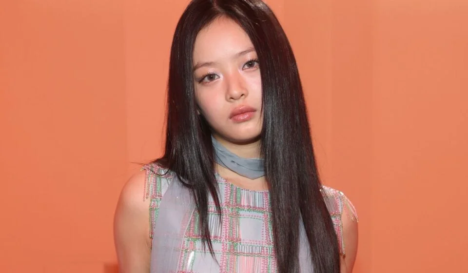 Женщина с длинными черными волосами на фоне оранжевой стены