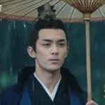 Молодой человек под зонтом в традиционной одежде