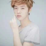 Молодой человек с короткими светлыми волосами в серой футболке