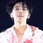 Человек в белой рубашке с красными узорами на сцене