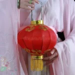 Человек в традиционной одежде держит красный фонарь