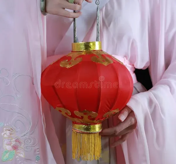 Человек в традиционной одежде держит красный фонарь