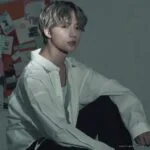 Человек в белой рубашке сидит перед доской с фотографиями.