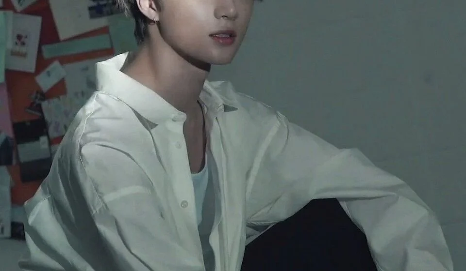 Человек в белой рубашке сидит перед доской с фотографиями.