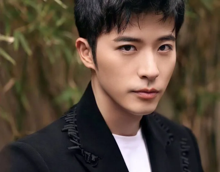 Молодой человек в черном пиджаке на фоне бамбука