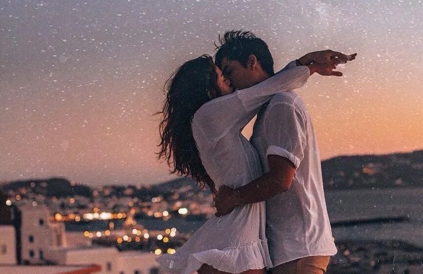 Романтический закат у моря, пара обнимается на фоне заката