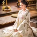 Женщина в традиционном азиатском платье сидит на полу.